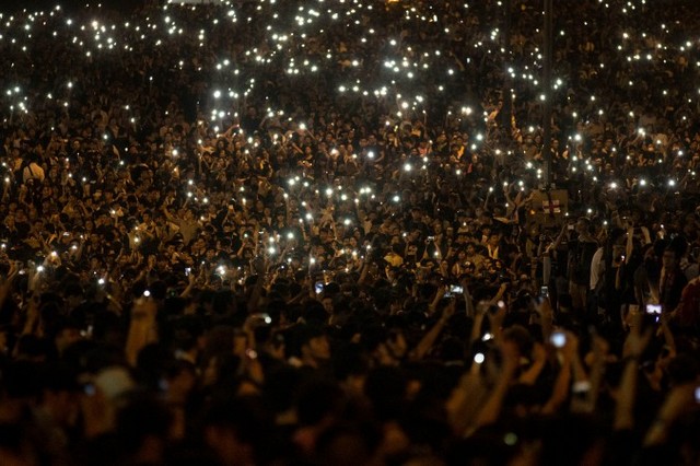 Протестующие машут своими мобильными телефонами перед зданием правительства Гонконга 29 сентября 2014 года. В Китае информация об акциях протеста в Гонконге была заблокирована, но многие материковые китайцы всё-таки сумели высказаться в интернете в их поддержку