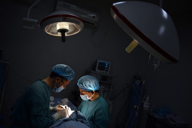 Два хірурги 9 серпня 2013 року проводять хірургічну операцію в Чунціні, що на південному заході Китаю. Пацієнт, який приїхав до Тяньцзіня для трансплантації, протягом лиш одного місяця отримав відповідну печінку і нирку