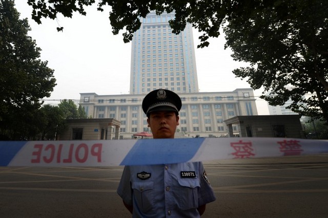 Поліцейський стоїть на варті біля Проміжного народного суду в місті Цзінані провінції Шаньдун, 24 серпня 2013 року