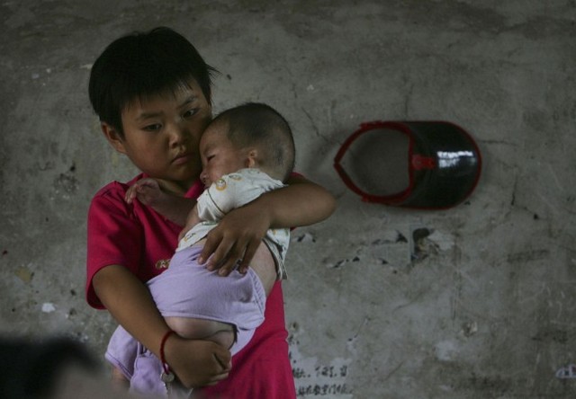 Десятирічний Ван Хуайсюе тримає немовля. Притулок у селі Саньшиліпу китайської провінції Аньхой, 9 липня 2006 року. Їх обох усиновили