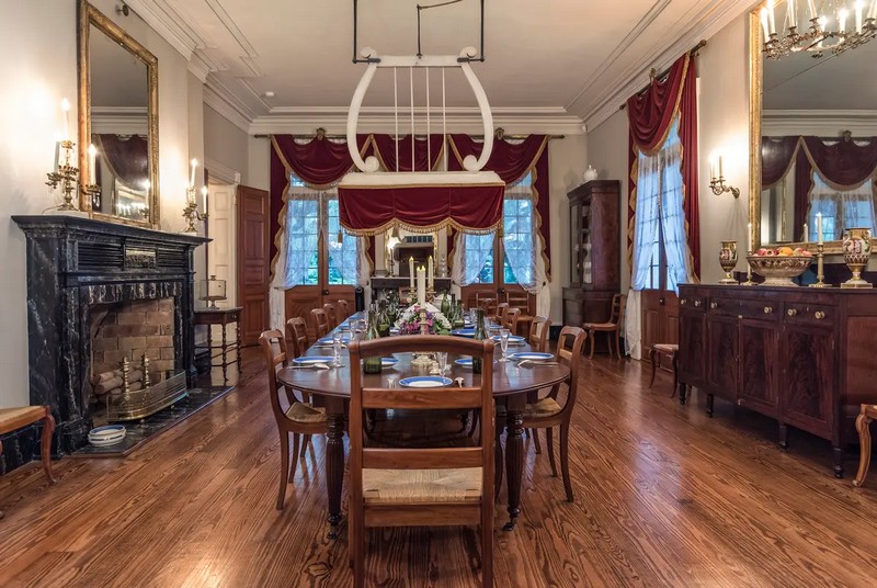 Над обеденным столом висит так называемый веерный вентилятор, являющийся оригинальным элементом особняка. Этот уникальный вентилятор, напоминающий лиру по форме, происходит из Восточной Индии и назывался «пунка». Его предназначение заключалось в том, чтобы кто-то, обычно домашний раб в довоенное время, тянул за веревку, чтобы веер медленно качался вперед и назад, пока люди ели за обеденным столом. Поток воздуха мешал мухам садиться на еду и обеспечивал прохладу в жаркие летние дни. Багровые бархатные шторы с золотыми кистями величественно висят на высоких окнах под рельефным потолком. (Oak Alley Foundation)