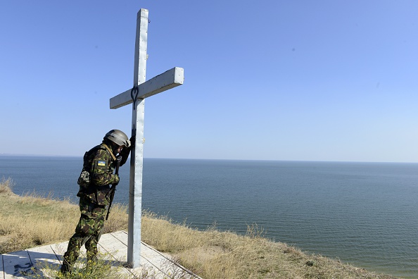 Український військовослужбовець батальйону Святої Марії молиться біля хреста, встановленого на березі моря у місті Маріуполь, 2 жовтня 2014 року. Фото: Alexander KHUDOTEPLY/AFP/Getty Images
