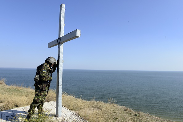 Украинский военнослужащий батальона Святой Марии молится возле креста, установленного на берегу моря у города Мариуполь, 2 октября 2014 года. Фото: Alexander KHUDOTEPLY/AFP/Getty Images