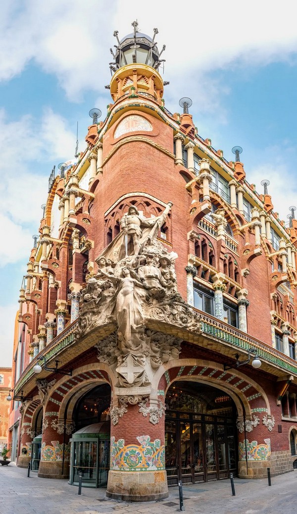 Південно-східний кут палацу, розташований на важливому перехресті, є центральною частиною його фасаду. Група класичних скульптур під назвою «Каталонська народна пісня» Мігеля Блая виділяється на тлі найбільш стриманої частини фасаду. Більшість фігур зображують каталонців у традиційному вбранні. Над ними стоїть Святий Георгій в обладунках — популярний покровитель Каталонії. Valerie2000/Shutterstock)