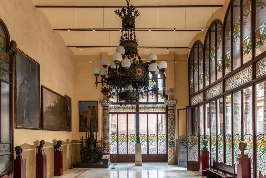 Названий на честь одного із засновників Orfeó Català, зал Lluís Millet має три скляні стіни з вишуканими кованими квітами, мозаїчними колонами та 650-фунтовою кованою люстрою в стилі мистецтва та ремесла. На стінах вишикувані бюсти постатей, пов'язаних із палацом або Orfeó Català, включаючи Мілле та його співзасновника Амадеу Вівеса. (agsaz/Shutterstock)