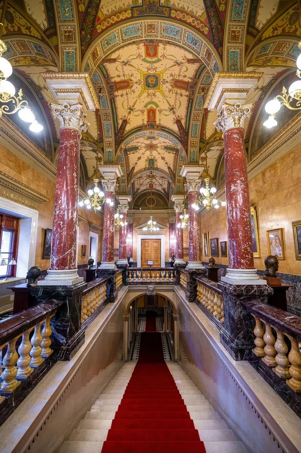 Від зовнішнього пандуса для екіпажів до внутрішньої частини Угорської державної опери ведуть так звані Королівські сходи, оскільки через цей вхід члени королівської родини могли непомітно потрапити до будівлі. Вісім червоних мармурових колон на білосніжних каррарських мармурових основах стоять на зеленуватих флорентійських мармурових п'єдесталах. Флорентійські мармурові перила перемежовуються жовтими балюстрадами з сієнського мармуру. Стеля прикрашена розписами з міфологічними істотами. (Mitzo/Shutterstock)