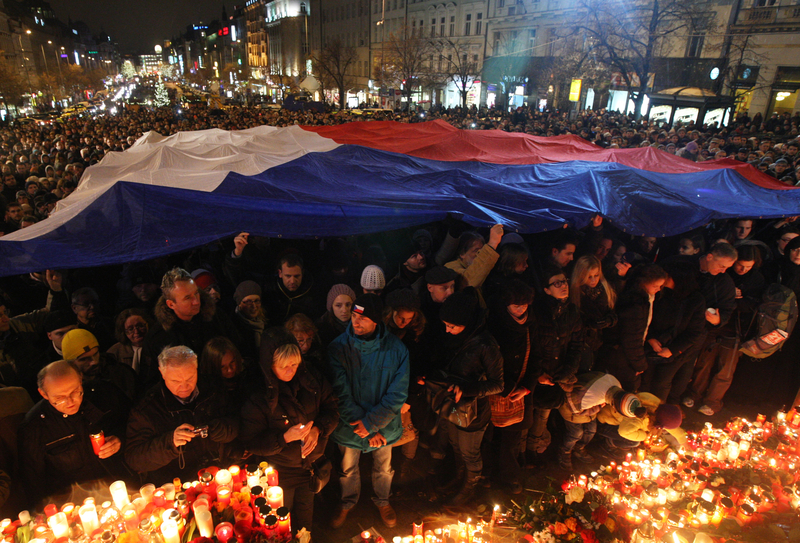 Люди с флагом Чешской Республики зажигают свечи в память о Вацлаве Гавеле на Вацлавской площади. Фото: Milan Malíček, Právo