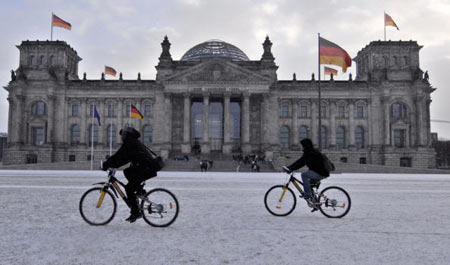 Два велосипедиста едут по первому снегу в Берлине мимо здания Бундестага (федеральный парламент) Фото: THEO HEIMANN/AFP/Getty Images