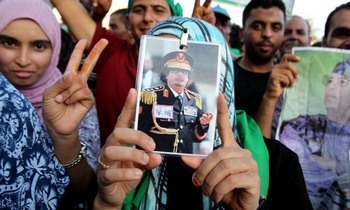 Прихильники Муамара Каддафі тримають портрет свого лідера. Фото: MAHMUD TURKIA/AFP/Getty Images