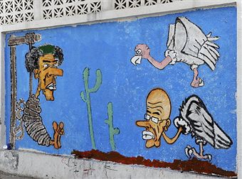 На карикатурі, намальованій фарбами на стіні 2 вересня 2011, зображений колишній лівійський лідер Муамара Каддафі, що звисає з шибениці в центрі міста Тріполі. Фото: Francisco Leong / Getty Images