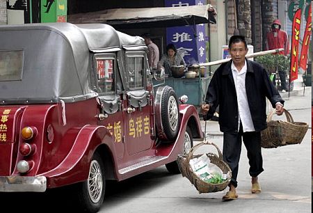 Ічан, провінція Хубей. Старий продавець овочів проходить повз шикарне авто. Фото: GOH CHAI Hin/afp/getty Images