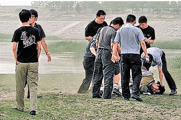 Полицейские бьют деятеля искусств, который через композицию в стиле Action art выразил своё недовольство правительством. Окрестности Пекина. Июнь 2010 год. Фото с kanzhongguo.com