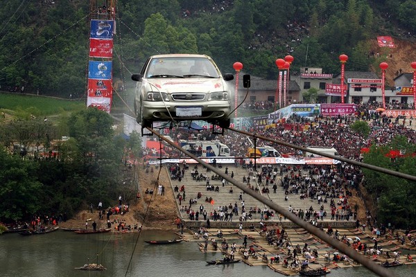 Г-н Лю Сочжу на машине пересёк реку по двум полоскам проволоки на высоте 45 м. Фото: The Epoch Times