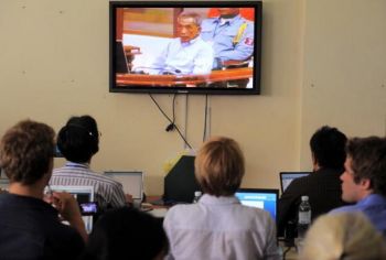 Місцеві та міжнародні журналісти дивляться пряму трансляцію з прес-центру Надзвичайної судової палати Камбоджі в Пномпені, 26 липня. На відео показують колишнього червоного кхмера на прізвисько «Дуч», під час винесення йому вироку судом за всі скоєні ним 