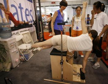 17 липня 2006 жінка тестує тренажер для виконання вправ пілатесу на фітнес-виставці в Пекіні. Фото: Frederic J. Brown / AFP / Getty Images