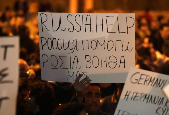 Кіпріот тримає в руках плакат з проханням до Росії надати острову фінансову допомогу. Фото: PATRICK BAZ / AFP / Getty Images