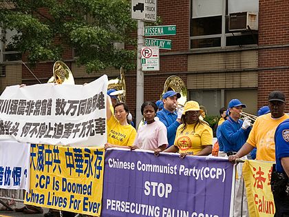 Сторонники Фалуньгун держат плакаты, в то время как позади них играет «Небесный оркестр». Фото: Дай Бин /The Epoch Times