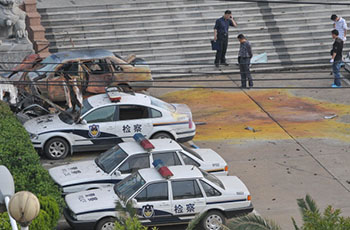 Посадові особи стоять поряд з пошкодженими автомобілями біля адміністративної будівлі після вибуху в місті Фучжоу східної провінції Цзянси 26 травня 2011. Фото: STR/AFP/Getty Images