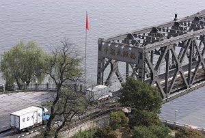 Китайські вантажівки, що прямують до Північної Кореї, вишикувалися перед Мостом дружби через річку Ялу, що сполучає дві країни, очікуючи інспекцію китайських військових офіцерів у прикордонному місті Даньдун, провінція Ляонін, Китай. Фото: Цаньцань Чу/ Ge