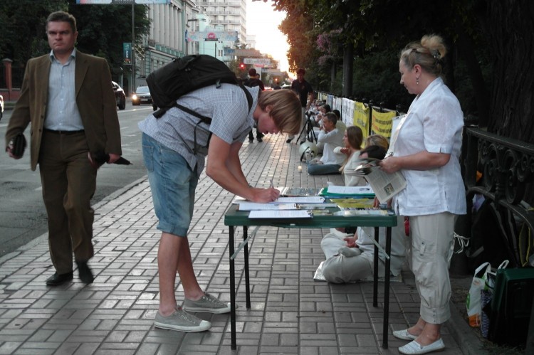 Молодий чоловік підписує петицію за припинення репресій проти послідовників Фалунь Дафа в КНР. Фото: Володимир Бородін/Велика Епоха