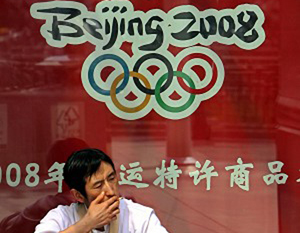 Мужчина курит на фоне рекламы Олимпийских игр-2008 в центре Пекина. Фото: Teh Eng Koon/AFP/Getty Images