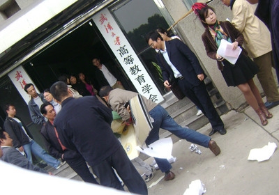 Неизвестные люди, вызванные администрацией, пытаются сорвать плакаты и забрать у студентов листовки. Фото с epochtimes.com