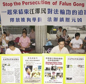 Практикующие Фалуньгун держат плакаты, призывая положить конец преследованию в Китае. Фото: Ted Aljibe/AFP/Getty Images