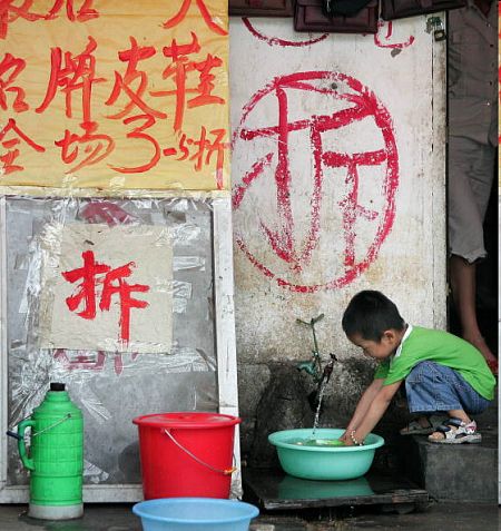 Пекін. Хлопчик, що набирає воду в таз біля свого будинку. Цей будинок за наказом мерії скоро зруйнують. Фото: FREDERIC J. Brown/afp/getty Images