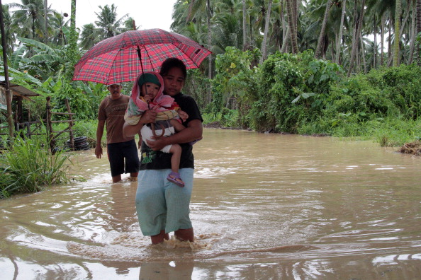 Філіппінка несе дитину через затоплену дорогу, острів Мінданао, 4 грудня 2012 Фото: STR / AFP / Getty Images