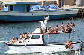 Туристическое судно проходит мимо баркаса, на котором итальянской береговой охраной были обнаружены 25 умерших африканских беженцев. Фото: Alessia Капассо / Getty Images