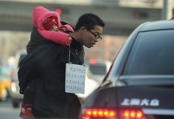 На улице Пекина мужчина с ребёнком просит милостыню. Фото: PETER PARKS/AFP/Getty Images