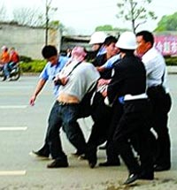 Полицейские и городские контролёры грубо арестовывают корреспондента Чена Юна. Фото сделано местным жителем с помощью мобильного телефона