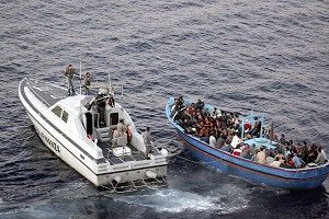 Наплив біженців: Італійський поліцейський катер наближається до судна з нелегальними емігрантами біля берегів о. Лампедуза в Італії, на початку літа. Щорічно десятки тисяч емігрантів висаджуються на італійські береги, більшість з них із Північної Африки.