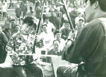 Когда Ци Сяочунь было шесть лет, отец научил ee играть на эрху, они играли с ним ежедневно. Во время репетиций они часто были окружены толпой людей, которая часами слушала музыку, отбивая такт руками и ногами. Фото: The Epoch Times