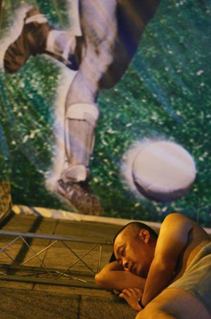 Сон на вулиці перед рекламним футбольним щитом. Фото: China Photos/getty Images 