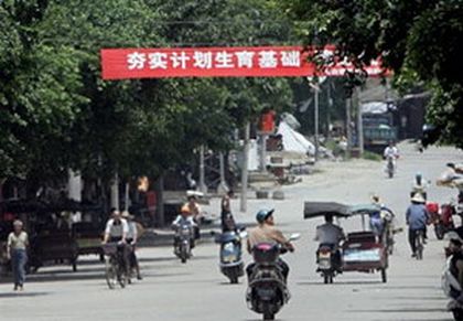 У селищі Побай провінції Гуансі над дорогою висить транспарант із написом: «Втілимо в життя закон про контроль народжуваності». Фото: AFP