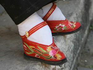 Мініатюрні перев'язані тканиною ступні в туфлях, розшиті лотосами. Фото: Getty Images