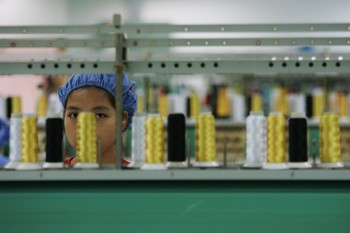 Работник у прядильной машины за конвейерной линией на фабрике Da Lang Wealthwise Plastic Factor в городе Донгуань провинции Гуандун 4 сентября 2007. Недавнее закрытие швейной фабрики Dingjia Knitting Company вызвало сильный страх относительно широкого рас