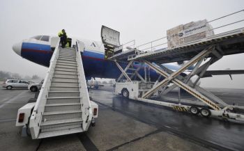 Работники загружают на самолет DC-10 водообрабатывающую установку, отправляемую немецким Красным Крестом в Зимбабве в связи со вспышкой холеры, аэропорт Шонефельд, 17 декабря 2008 г. Фото: John MacDougall /AFP /Getty Images