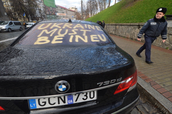Міліціонер проходить повз автомобіля, на задньому склі якого написано: «Україна має бути в ЄС», Київ, 2 грудня 2013 р. Фото: SERGEI SUPINSKY/AFP/Getty Images