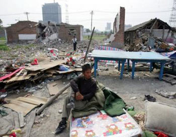 Житель Пекина сидит на матрасе на месте разрушенного дома в районе Таянгун, 10 мая 2007 г. В ночь на 9 мая неизвестными было снесено около 26 домов. Жилищная реформа в Китае приводит к лишению людей своего жилья. Фото: China Photos/Getty Images