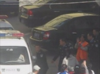 Після суду Ху Цілі в наручниках саджають у поліцейську машину. Перед машиною її родичі. Фото з epochtimes.com 
