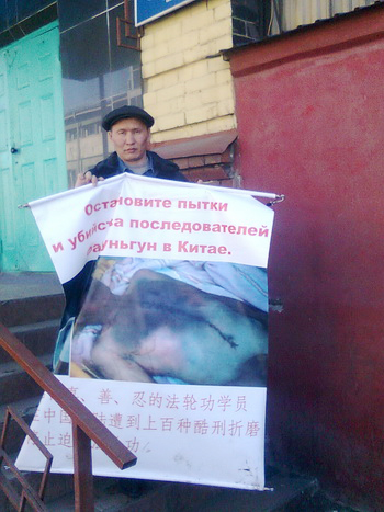 Эдуард Кузьмин возле ОВД Куйбышевского района г. Иркутска с плакатом, на котором переломлена медная трубка диаметром 16 мм. Фото предоставлено Эдуардом Кузьминым