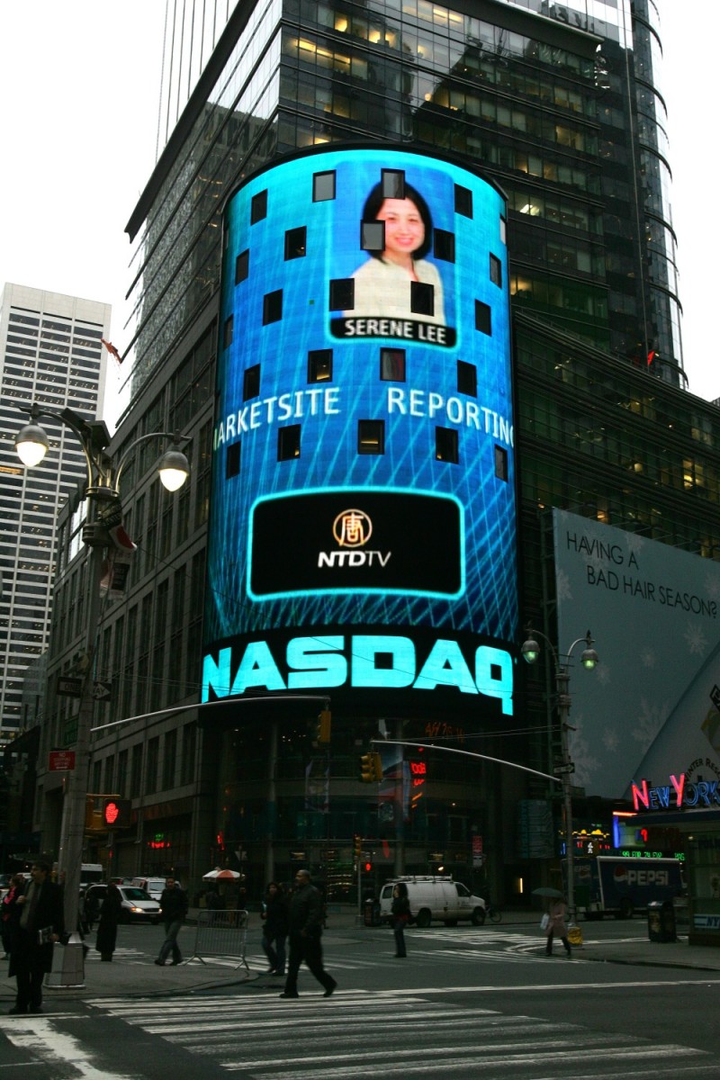 Серена Лі і логотип телеканалу New Tang Dynasty на інтерактивному рекламному майданчику офісу NASDAQ's на Таймс-сквер, в 2007 році, незадовго до того як під тиском компартії Китаю їй закрили пропуск до будівлі NASDAQ. Фото: NTD Television