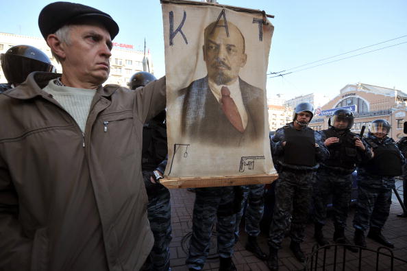 Чоловік тримає портрет Леніна з написом 'КАТ' біля ОМОНу на акції українських комуністів під час відкриття відреставрованого пам'ятника Леніна. Київ, 27 листопада 2009 року. Фото: SERGEI SUPINSKY/AFP/Getty Images