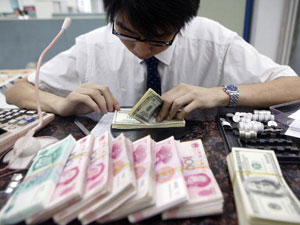 Клерк шанхайського банку перераховує пачки юанів і доларів. (ChinaPhotos/Getty Images)