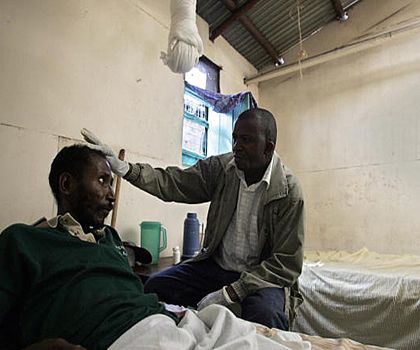 Чарльз Каїб (справа), волонтер, який працює з ВІЛ-інфікованими та хворими на СНІД у хащах Корогочо у східній частині Найробі, доглядає за пацієнтом у клініці при католицькій церкві. Фото: Simon Maina /AFP /Getty Images