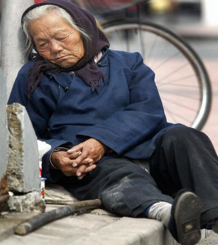 Пекин. Пожилая женщина отдыхает на тротуаре. Фото:Frederic J.Brown/AFP/Getty Images