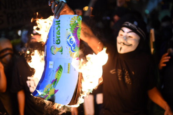 Демонстранти палять рекламні проспекти і символи ЧС з футболу-2014 в Бразилії під час акції протесту 15 травня проти майбутнього чемпіонату з футболу в Ріо-де-Жанейро. Фото: CHRISTOPHE SIMON/AFP/Getty Images