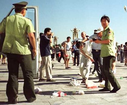 Полицейские арестовывают последовательницу Фалуньгун, протестующую против репрессий. Фото с epochtimes.com